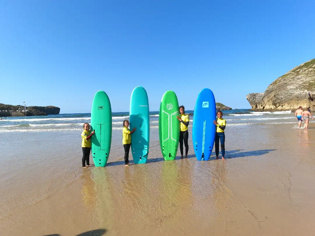 Grupo de niños de varios tamaños posando con su tabla de surf en Celorio
